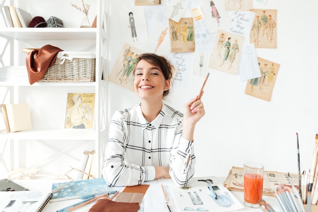 Portrait of a smiling fashion designer woman holding paintbrush