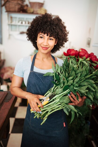 Portrait of a smiling female florist with bunch of red flowers