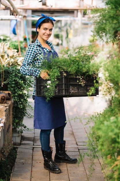 Портрет улыбающегося садовода, держит ящик со свежими растениями