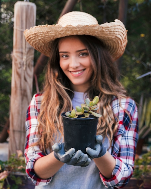 黒いサボテンの植物を保持している手袋を身に着けている笑顔の女性の肖像画