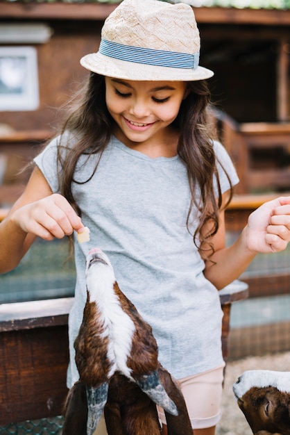 Free photo portrait of a smiling girl feeding to goat