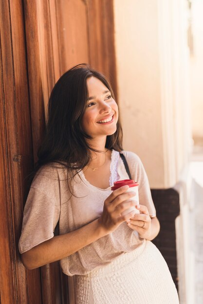 使い捨てコーヒーカップを持っている笑顔の女の子の肖像