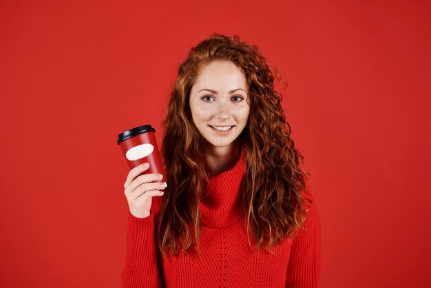 コーヒーの使い捨てマグカップを保持している笑顔の女の子の肖像画