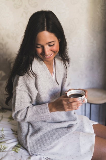 Ritratto di una ragazza sorridente che guarda giù tenendo tazza di caffè