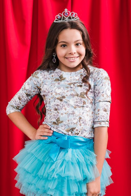 Portrait of smiling girl standing in front of red curtain