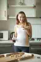 Free photo portrait of smiling girl standing, holding a slice of pizza