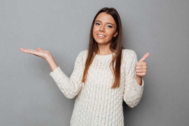 Portrait of a smiling girl in sweater holding copy space