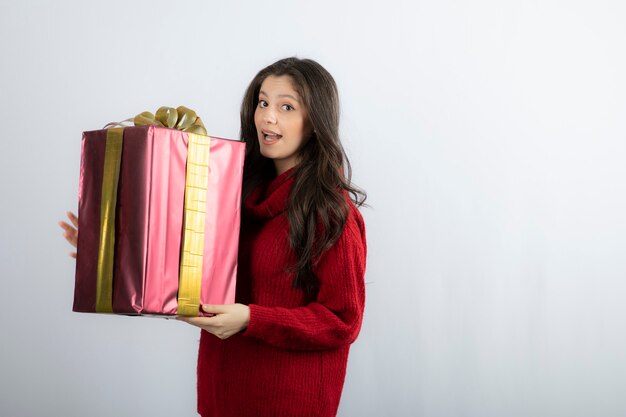 プレゼントボックスを保持しているセーターの笑顔の女の子の肖像画。