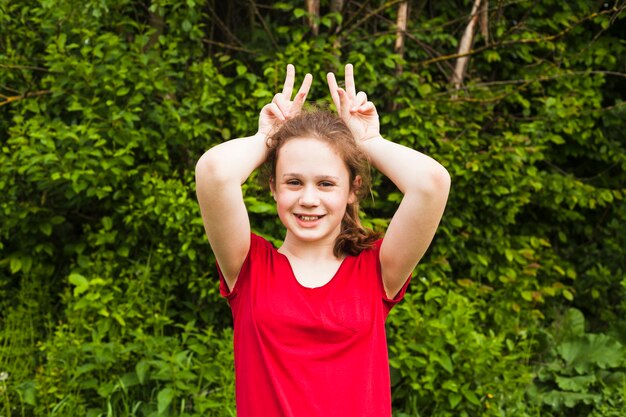 Portrait of smiling girl teasing with finger on hand in park