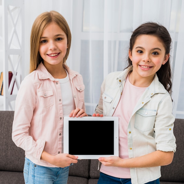 Portrait of a smiling girl wearing denim jacket showing digital tablet