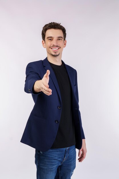 Portrait of smiling handsome businessman extend hand for handshake look friendly greet you hi gesture standing over white background