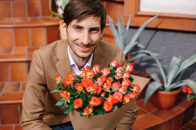 Portrait of smiling handsome man holding a bouquet of flowers