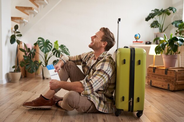 Portrait of smiling handsome young man holding flight tickets going on holiday sitting with green