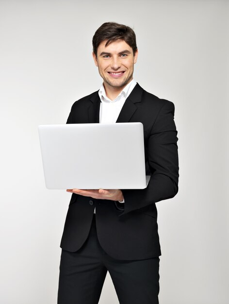 Portrait of smiling happy businessman with laptop in black suit