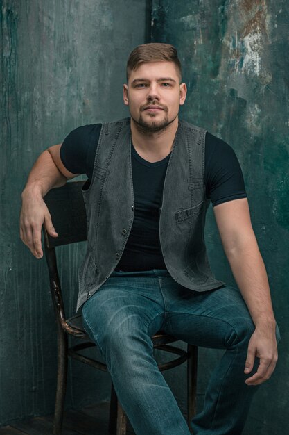 Portrait of smiling happy man sitting on the chair in studio