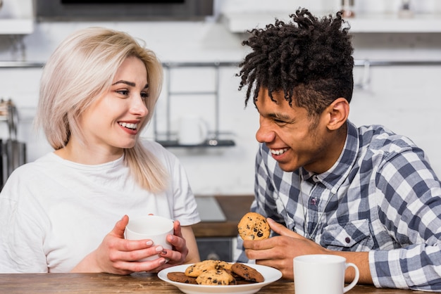 朝食を家で一緒に持っている笑顔の異人種間の若いカップルの肖像画