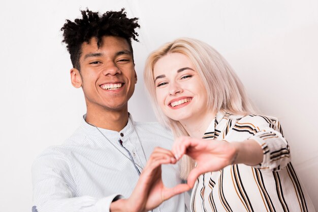 Portrait of smiling interracial young couple making heart shape with hands