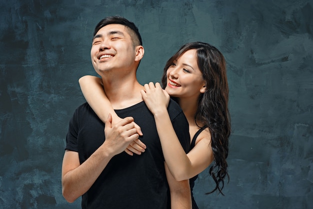 Портрет улыбающейся корейской пары в серой студии