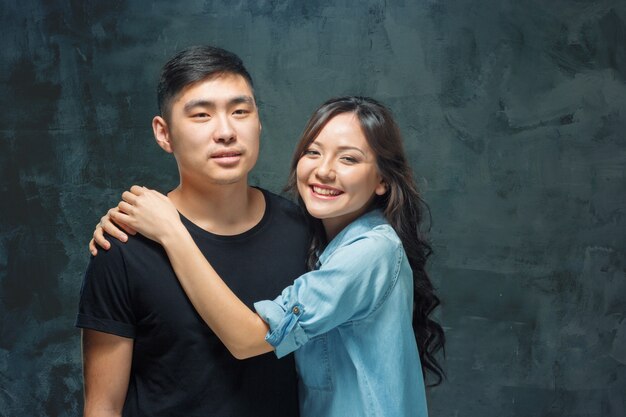 Portrait of smiling Korean couple on a gray wall