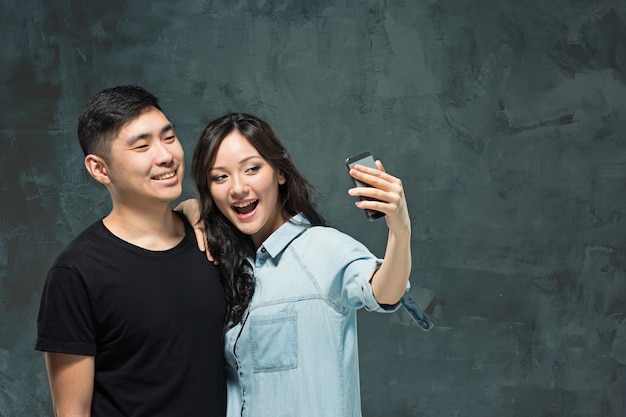 灰色の壁に韓国のカップルを笑顔の肖像画