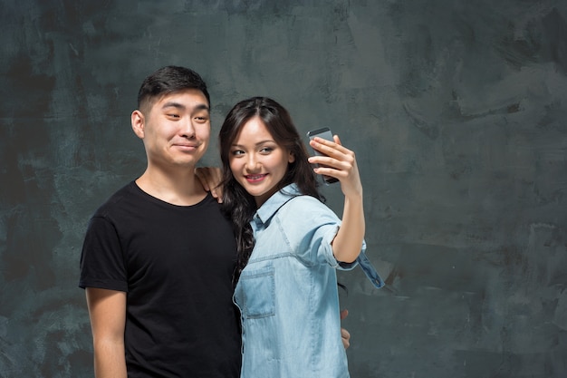 Portrait of smiling Korean couple on a gray