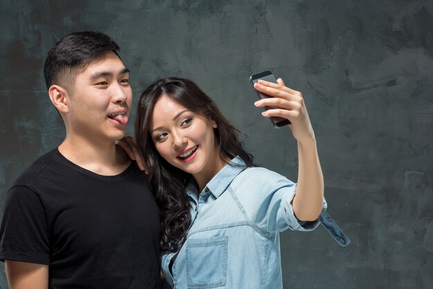 Portrait of smiling Korean couple on a gray