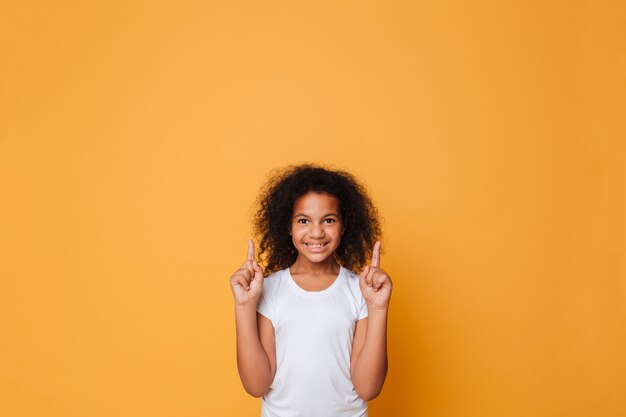 Портрет улыбающегося маленькая африканская девушка, указывая пальцами