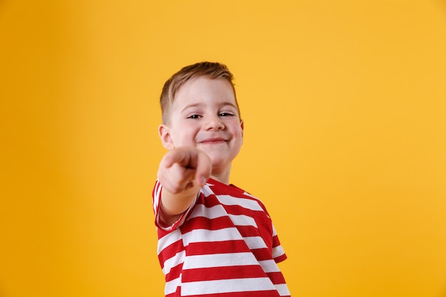 Foto gratuita ritratto di un ragazzino sorridente che punta il dito