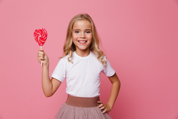 Il ritratto di una bambina sorridente che tiene il cuore ha modellato la lecca-lecca