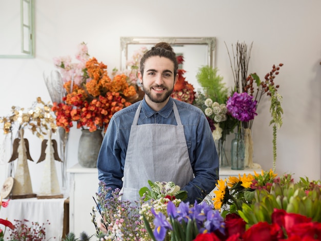 Portrait of a smiling male florist with colorful flowers in the shop