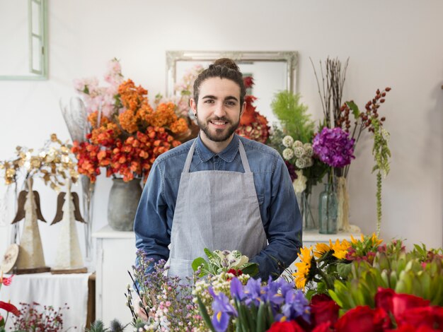 Portrait of a smiling male florist with colorful flowers in the shop