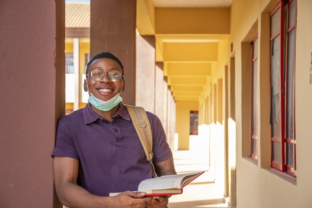 Ritratto di uno studente maschio sorridente con in mano un libro e sorridente