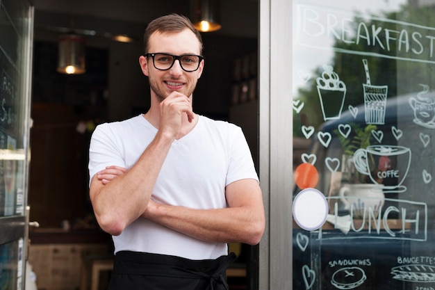 Портрет улыбающегося официанта мужского пола за пределами кафе