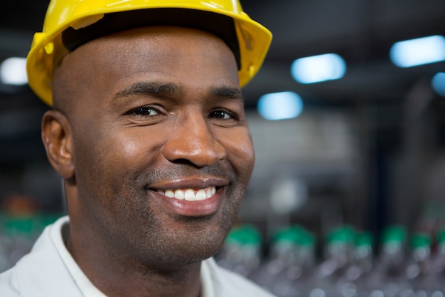 Портрет улыбающегося работника мужского пола в каске на складе
