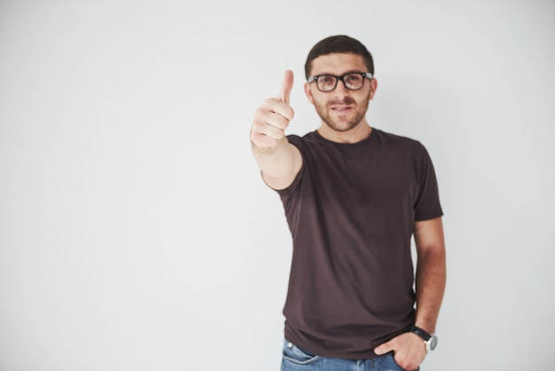 Ritratto di un uomo sorridente in vetri che mostra pollice in su sopra bianco