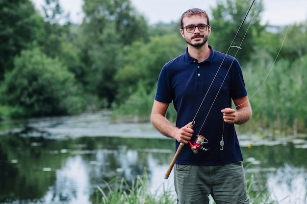 Portrait of smiling man holding fishing rod near the lake