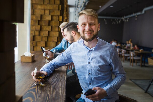 Portrait of smiling man holding glass of drink in the bar