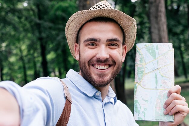 屋外でselfieを取って地図を持って笑みを浮かべて男の肖像