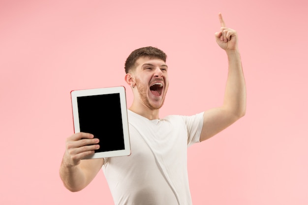Портрет улыбающегося человека, указывающего на ноутбук с пустым экраном, изолированным на розовой студии