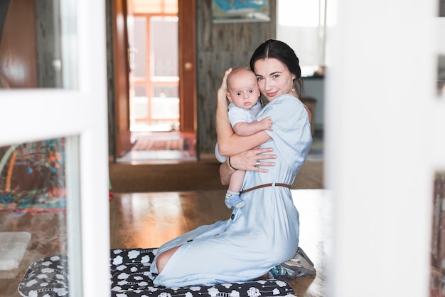 Portrait of smiling mother embracing her baby at home