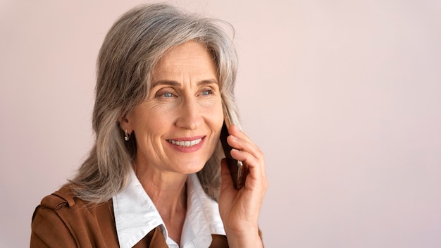 Портрет улыбающейся пожилой женщины, разговаривающей по телефону