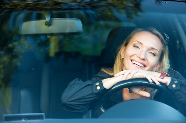 Foto gratuita ritratto di donna graziosa sorridente nella nuova macchina - all'aperto