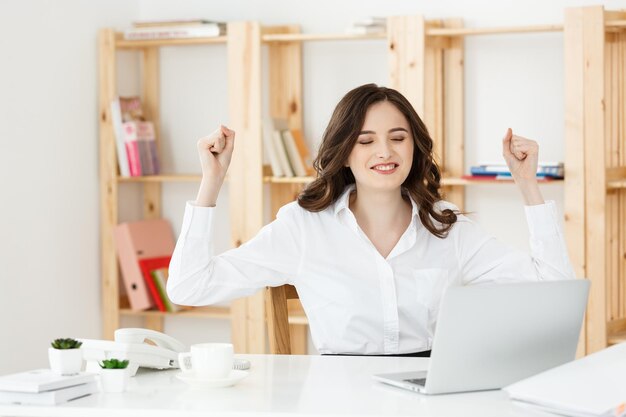 Portrait of smiling pretty young business woman sitting on workplace