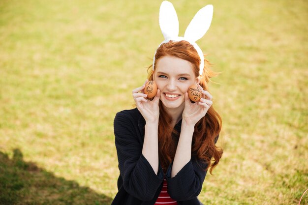 Portrait of a smiling red head woman wearing bunny ears