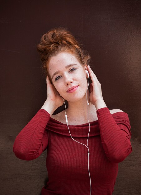 Portrait of smiling redhead woman listening to music