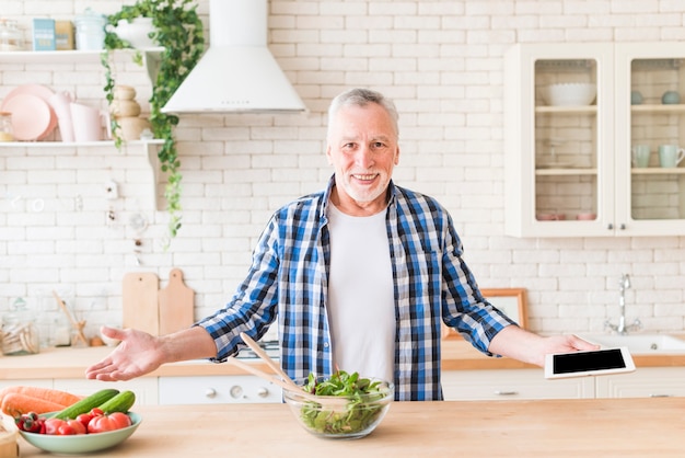 Portrait of a smiling senior man holding digital tablet in hand shrugging