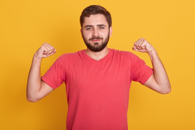 Portrait of smiling strong bearded men dresses casual red t shirt showing biceps