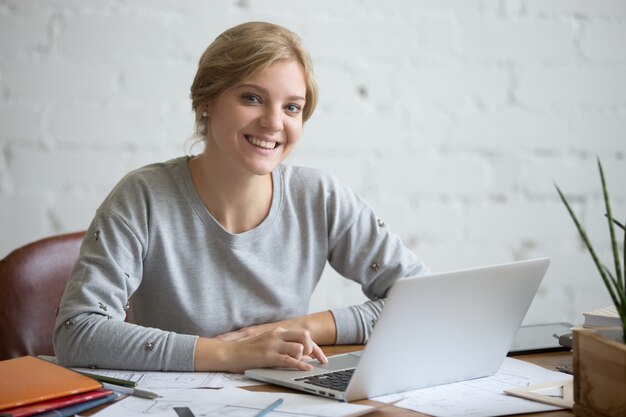 Портрет улыбающегося студента девушка на столе с ноутбуком