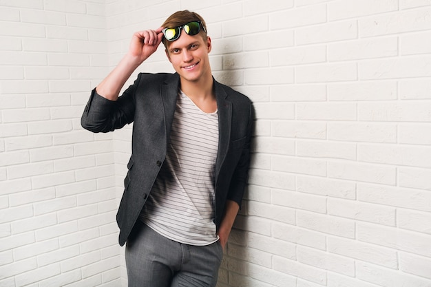 Portrait Of Smiling stylish man Standing Against Brick Wall In Modern Office