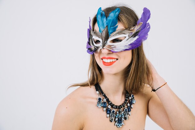 Portrait of a smiling topless woman wearing feather mask